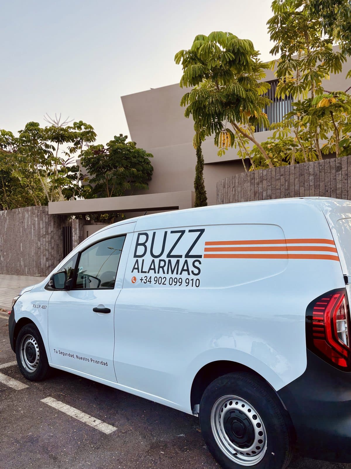 A Buzz Alarmas service van parked outside a property.